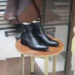 Side view of men’s black dress boots with a sleek buckle strap design.
