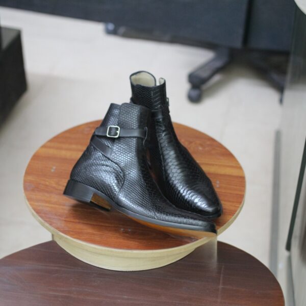 Side view of men’s black dress boots with a sleek buckle strap design.